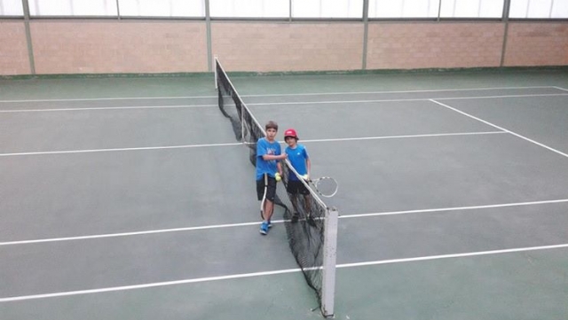dos ninos en una pista de tenis junto a la red.jpg